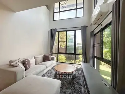 Spacious living room with large windows and modern furniture, offering a bright and airy ambiance.