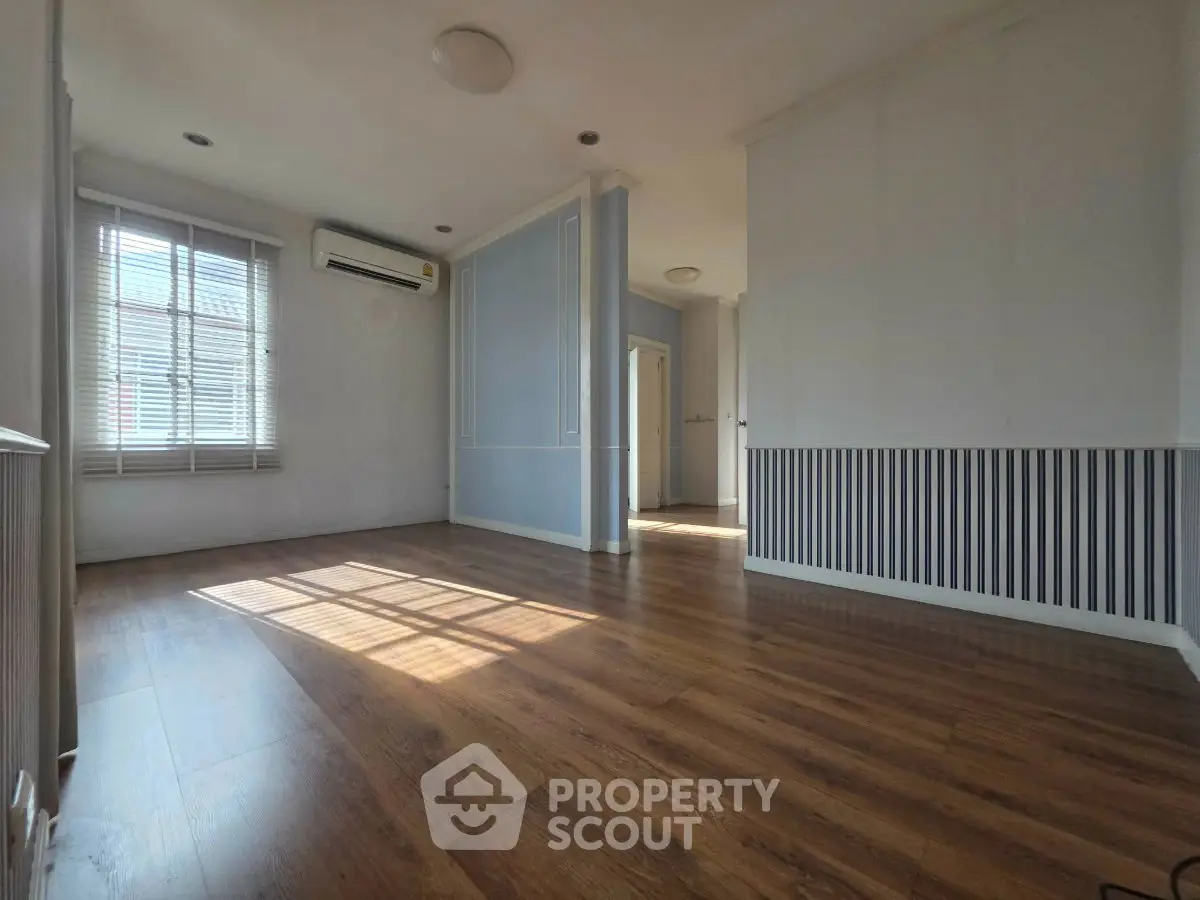 Spacious living room with wooden flooring and natural light, perfect for modern living.