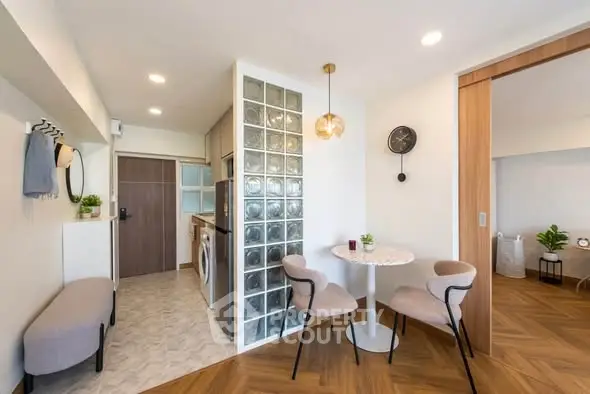 Modern open-plan living area with stylish dining set and glass block partition in a cozy apartment.