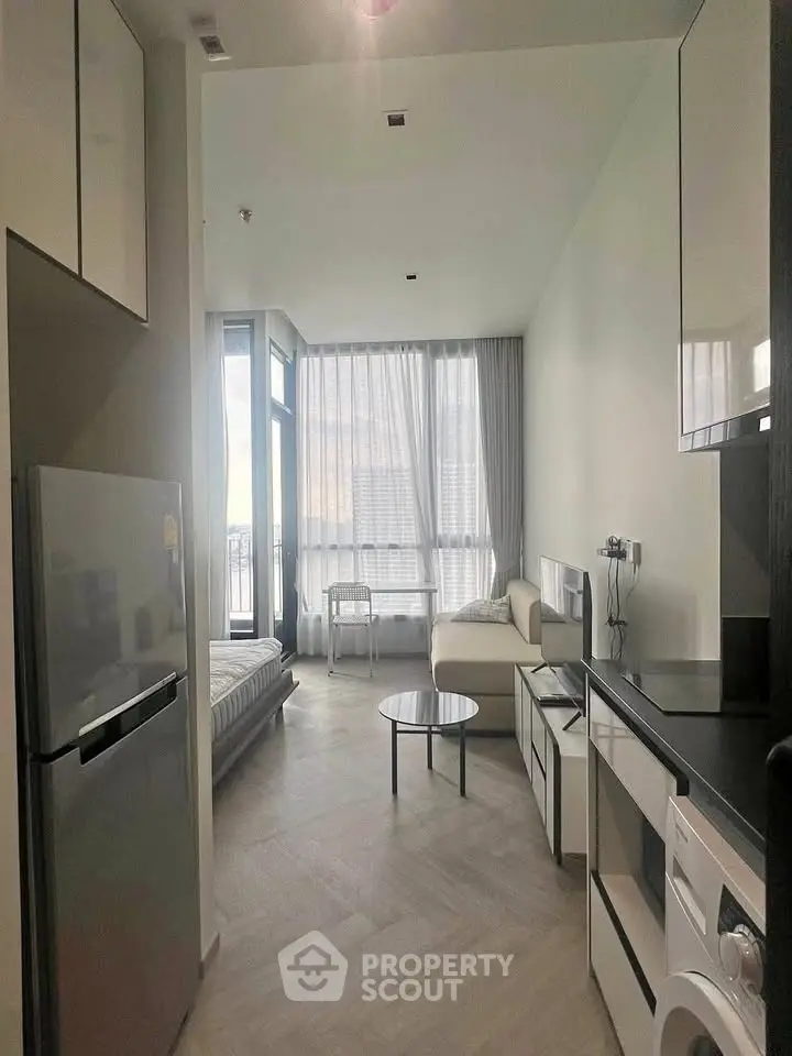 Modern studio apartment with open layout, featuring a compact kitchen, cozy living area, and large windows for natural light.