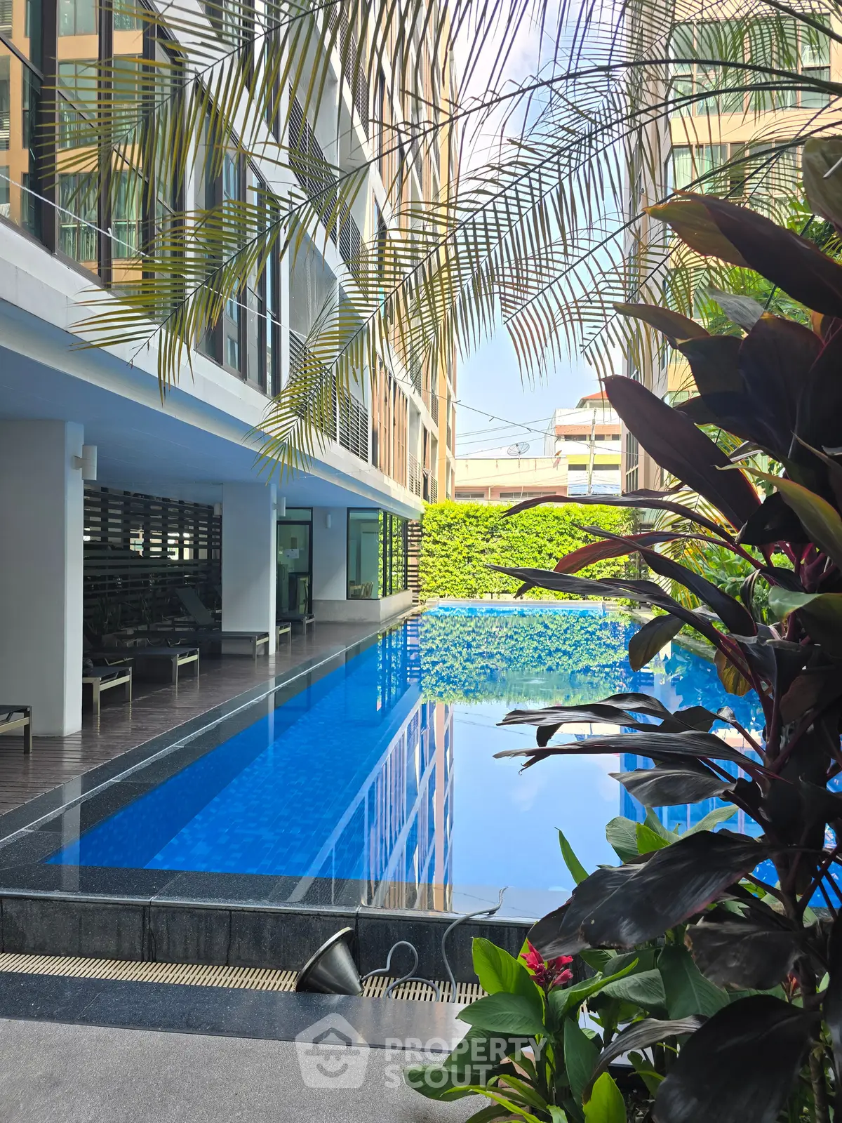 Luxurious residential building with a stunning outdoor pool surrounded by lush greenery.