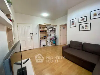 Cozy living room with wooden flooring, brown sofa, and wall-mounted shelves in a modern apartment.