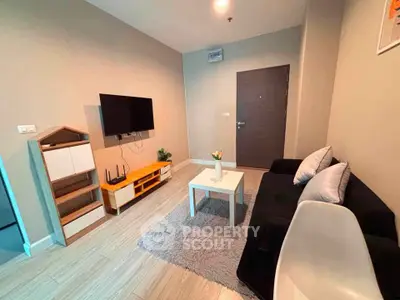 Modern living room with sleek furniture and wall-mounted TV in a cozy apartment.