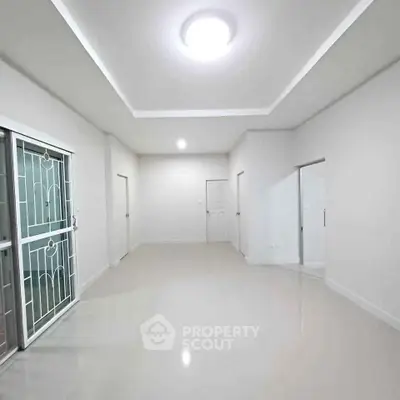 Spacious minimalist living room with sleek white walls and modern lighting.