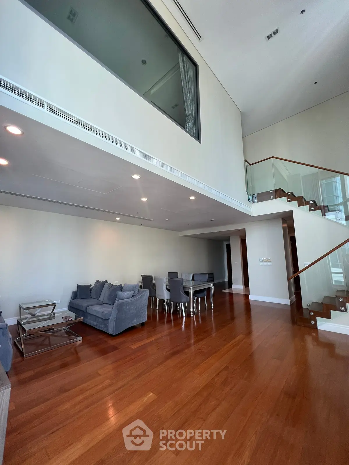 Spacious modern living room with high ceilings and elegant staircase in luxury apartment.
