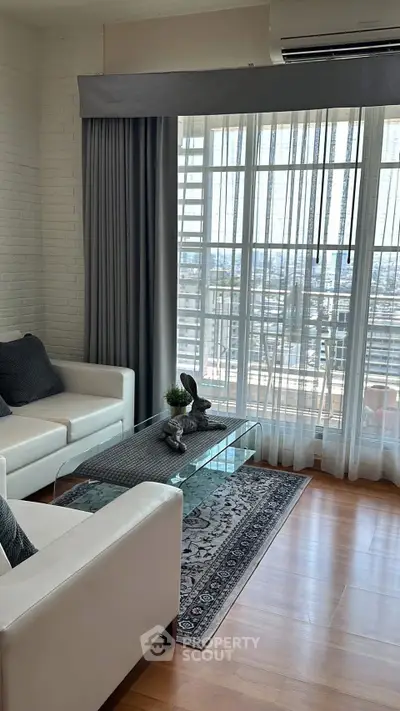 Elegant living room with large windows and city view, featuring modern furniture and stylish decor.