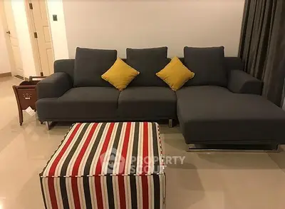 Modern living room with stylish gray sofa and colorful striped ottoman
