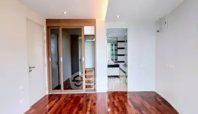 Spacious modern bedroom with wooden flooring and ensuite bathroom in luxury apartment.