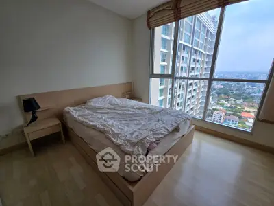 Spacious bedroom with large window offering stunning city views in modern high-rise apartment.