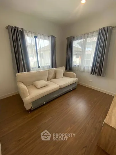 Cozy living room with elegant sofa and natural light from large windows.
