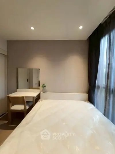 Cozy bedroom with natural light, featuring a bed, desk, and chair, ideal for relaxation and productivity.