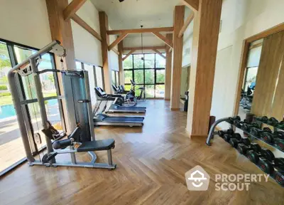 Spacious gym with modern equipment and pool view in luxury real estate property.