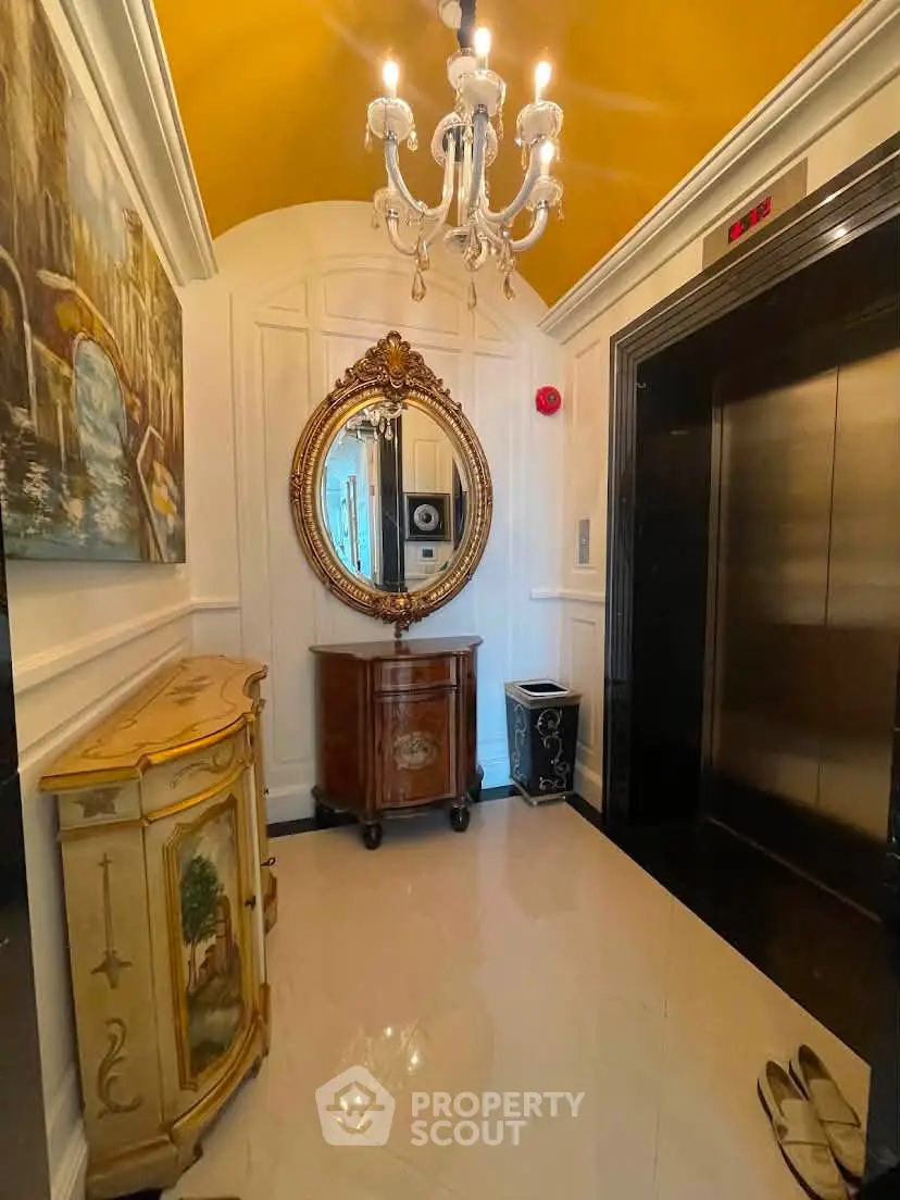 Elegant elevator lobby with chandelier and ornate mirror in luxury building