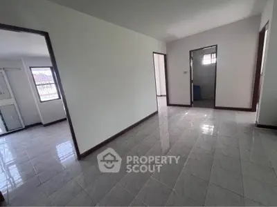 Spacious empty room with tiled flooring and multiple doorways