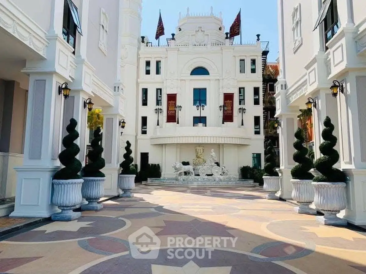 Luxurious building entrance with elegant architecture and decorative landscaping.