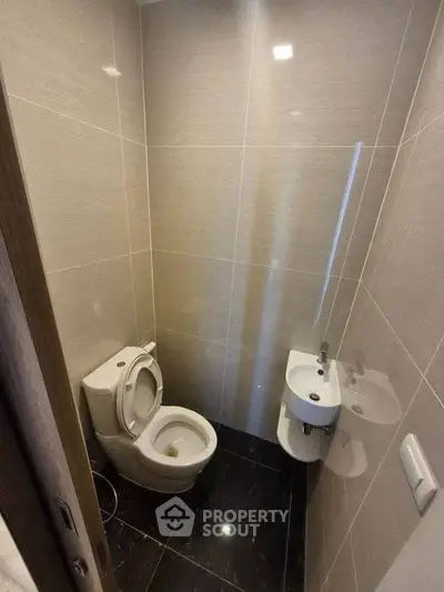 Compact modern bathroom with sleek fixtures and glossy tiles