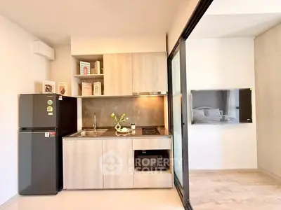 Modern compact kitchen with sleek appliances and open layout in stylish apartment.