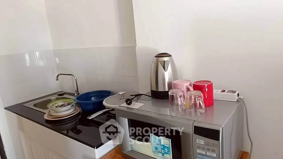Compact kitchen with modern appliances including microwave and electric kettle, ideal for efficient cooking.