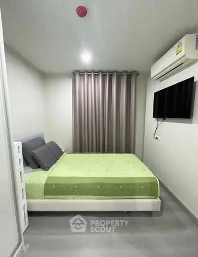 Modern bedroom with green bedding and wall-mounted TV in a cozy apartment.