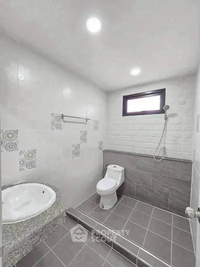 Modern bathroom with stylish tiles and sleek fixtures, featuring a shower and toilet in a bright, airy space.