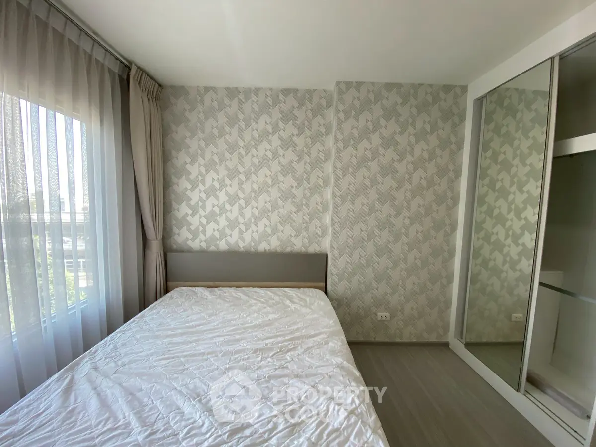 Modern bedroom with stylish wallpaper and large window for natural light.