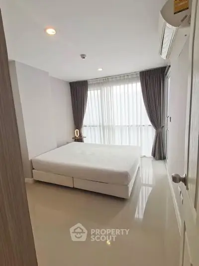 Spacious bedroom with large window and modern decor in a luxury apartment.