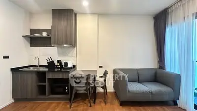 Modern compact living room with kitchenette, featuring sleek cabinetry and cozy seating area.