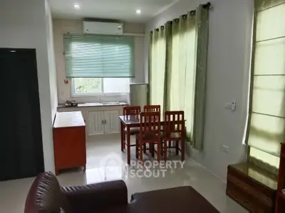 Cozy living room with dining area and natural light, featuring modern furniture and a compact kitchen.