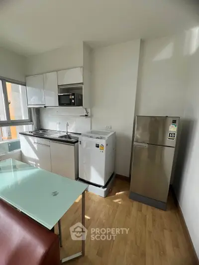 Modern kitchen with stainless steel appliances and sleek cabinetry in a bright apartment.