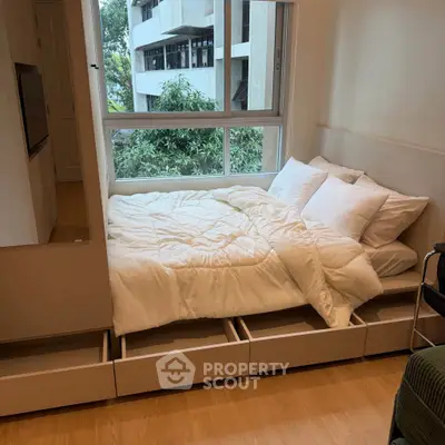 Cozy bedroom with built-in storage and large window offering a serene view, perfect for modern living.