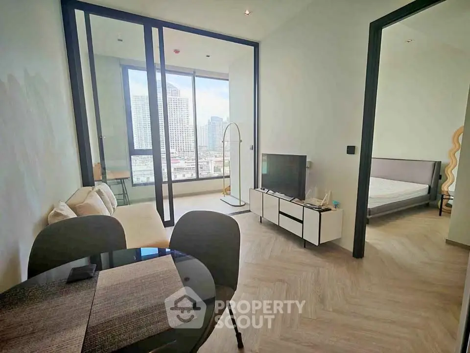 Modern apartment interior with living room and bedroom, featuring large windows and city view.