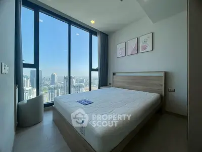 Modern bedroom with large window offering stunning city view in high-rise apartment.