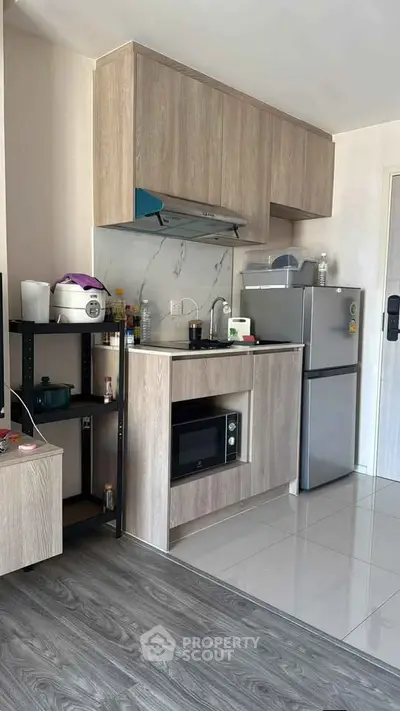 Modern compact kitchen with sleek cabinetry and stainless steel appliances in a stylish apartment.