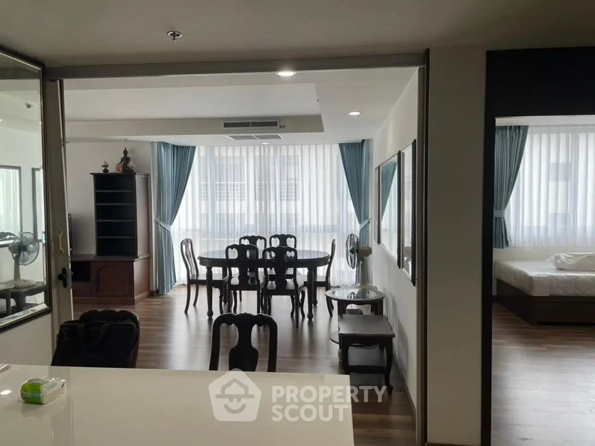 Spacious open-plan living and dining area with elegant wooden furniture and large windows.