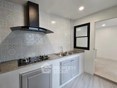 Modern kitchen with sleek design, featuring gas stove and stylish backsplash tiles.