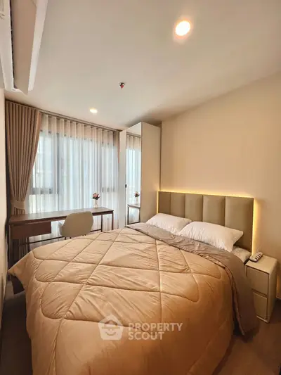 Cozy bedroom with modern decor and natural light, featuring a comfortable bed and stylish workspace.