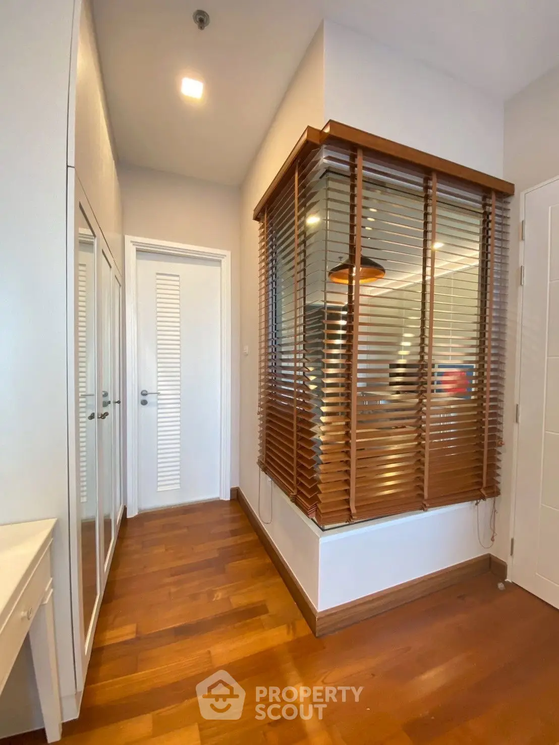 Modern hallway with wooden flooring and stylish blinds in a contemporary home.