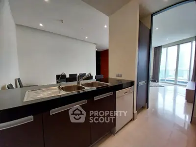 Modern kitchen with sleek design and open layout leading to a bright living area.