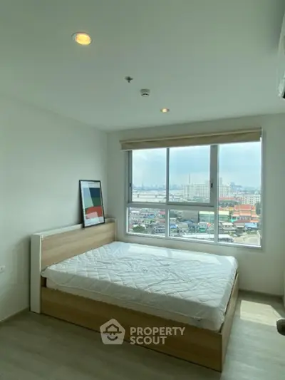 Modern bedroom with large window offering city view and natural light