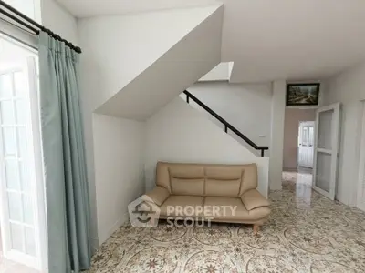 Spacious living room with stylish sofa and elegant tiled flooring under staircase.