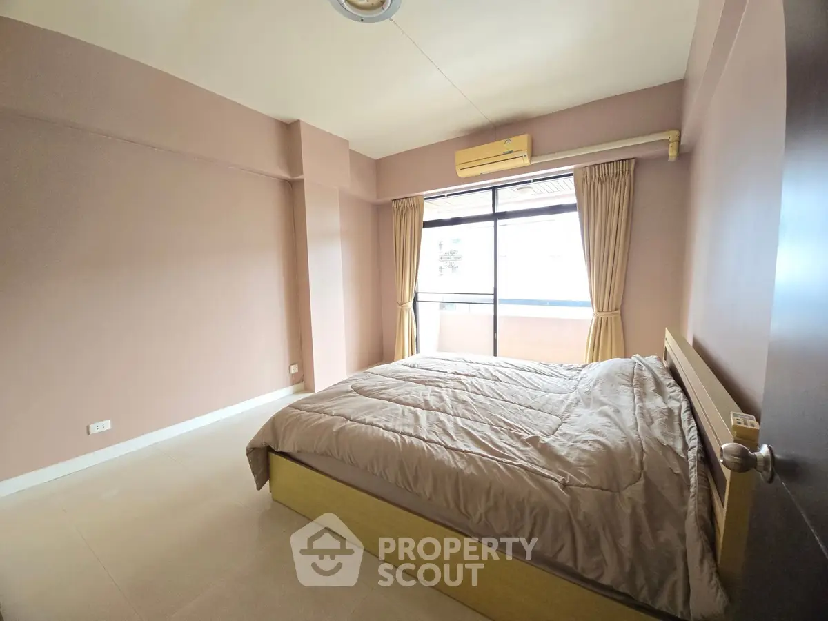 Spacious bedroom with large window and modern decor in a cozy apartment.