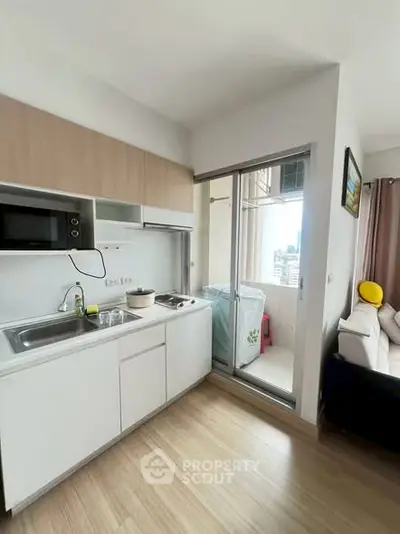 Modern compact kitchen with open layout and balcony view in urban apartment