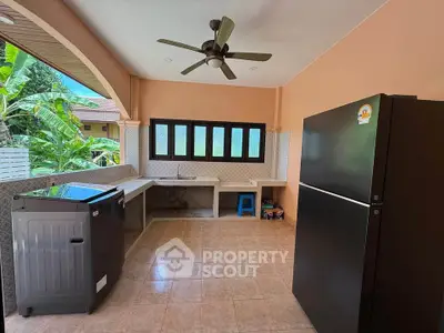 Spacious outdoor kitchen with modern appliances and ceiling fan