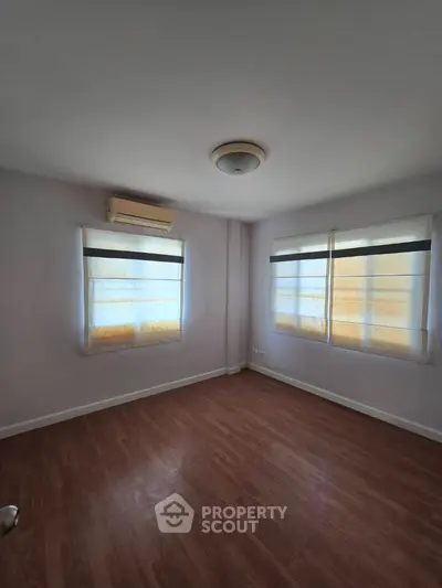 Spacious empty room with wooden flooring and large windows