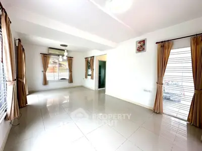 Spacious empty living room with large windows and tiled flooring