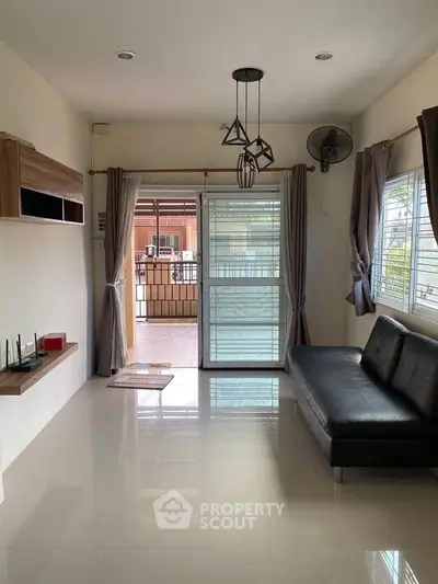 Modern living room with sleek black sofa and large windows for natural light.