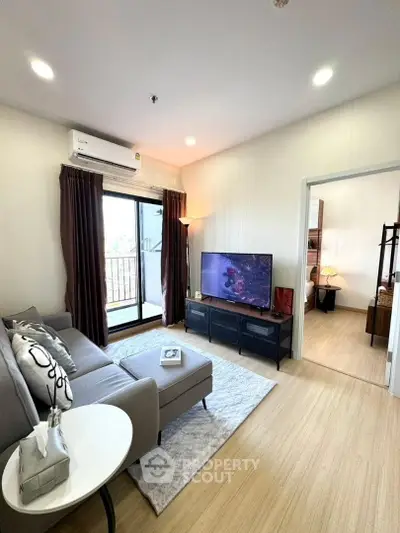 Modern living room with cozy sofa and large TV, featuring elegant decor and natural light from balcony.