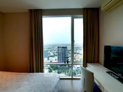 High-rise bedroom with stunning city view, modern desk, and cozy ambiance.