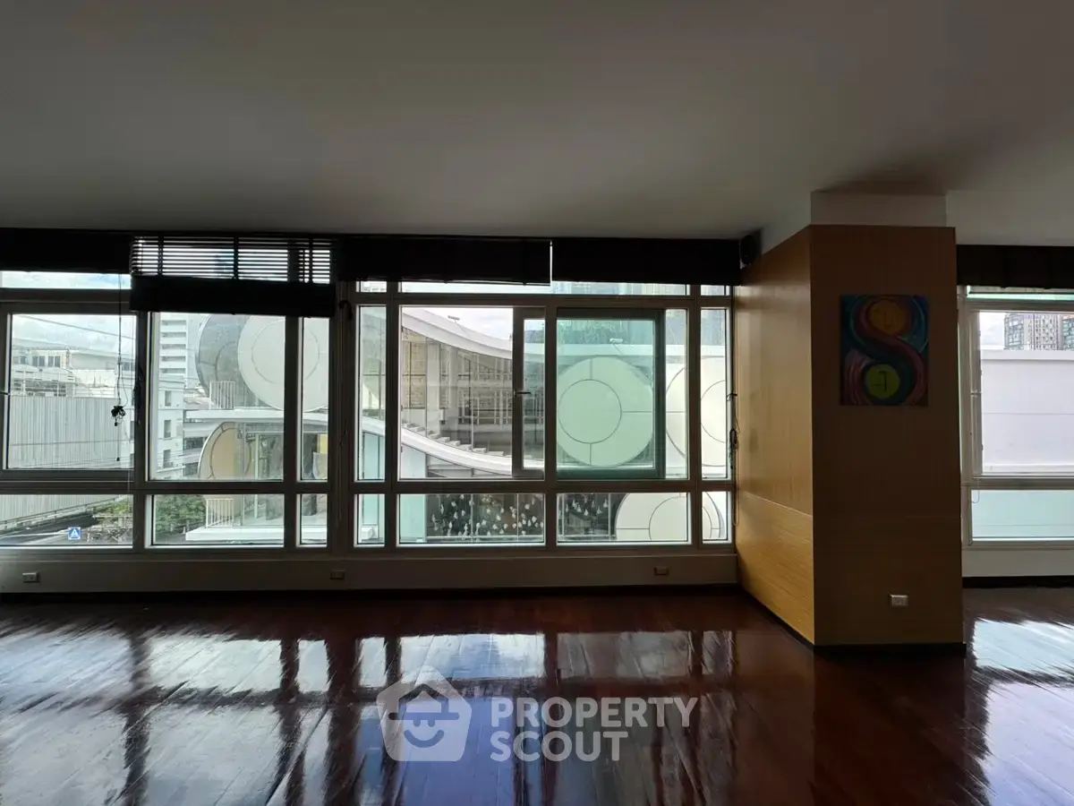 Spacious modern living room with large windows offering city views and elegant wooden flooring.