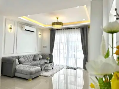 Luxurious living room with elegant decor and plush furniture, featuring a stylish chandelier and large windows.